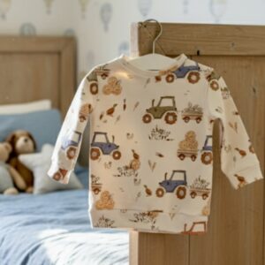 Baby wearing sky blue organic cotton sweater with harvest pattern